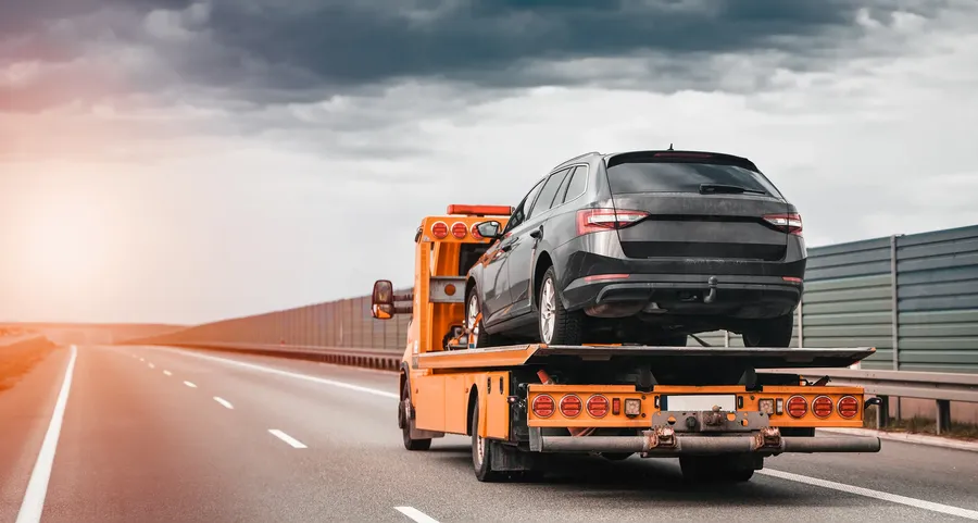 Flatbed wrecker hauling a car on the highway